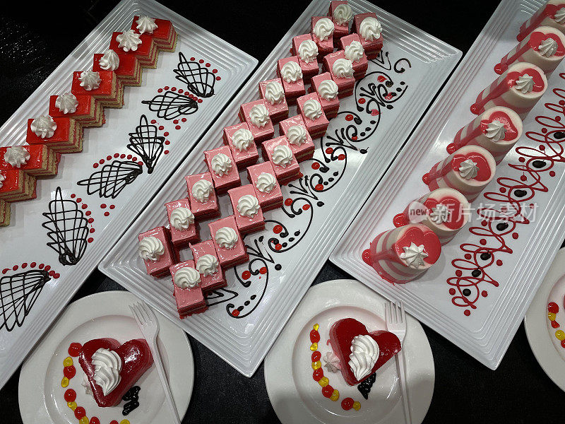 Showcase with sweets. Colored Ñakes on white plates on black table.